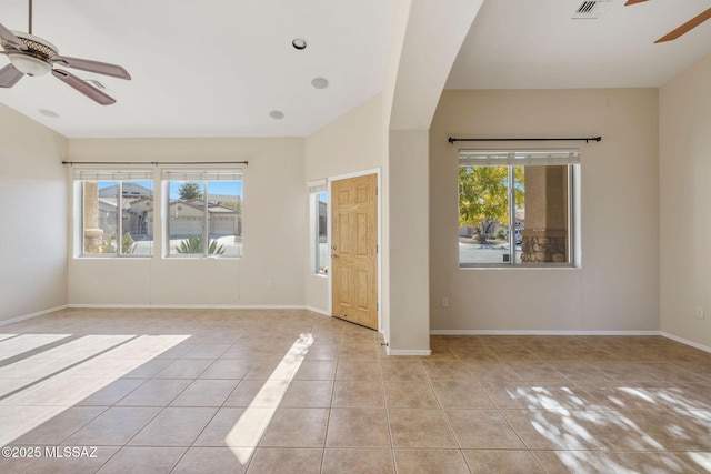 interior space with baseboards, light tile patterned flooring, ceiling fan, and a wealth of natural light