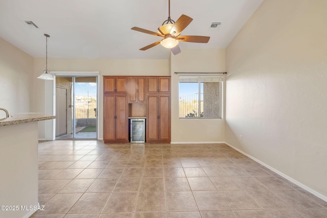unfurnished living room featuring visible vents, plenty of natural light, light tile patterned floors, and ceiling fan
