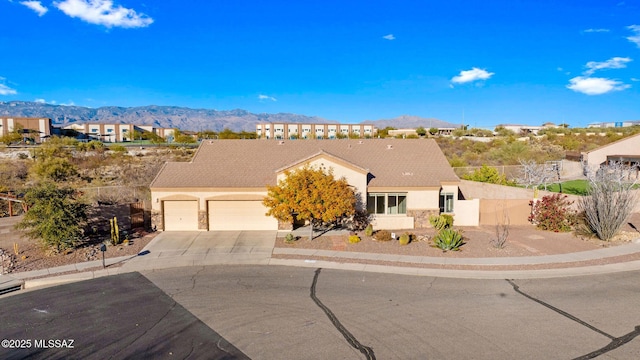 single story home featuring an attached garage, driveway, a mountain view, and stucco siding
