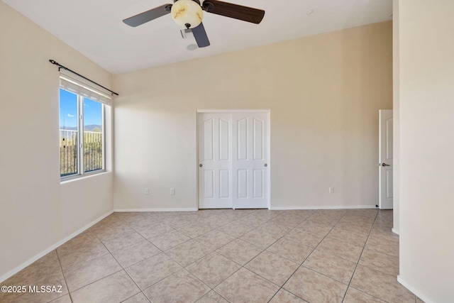 empty room featuring light tile patterned flooring, ceiling fan, and baseboards