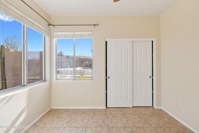 unfurnished room with baseboards, light tile patterned flooring, and a wealth of natural light