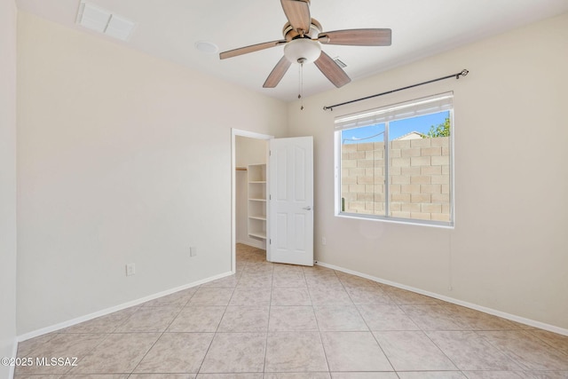 empty room featuring light tile patterned floors, baseboards, a ceiling fan, and visible vents