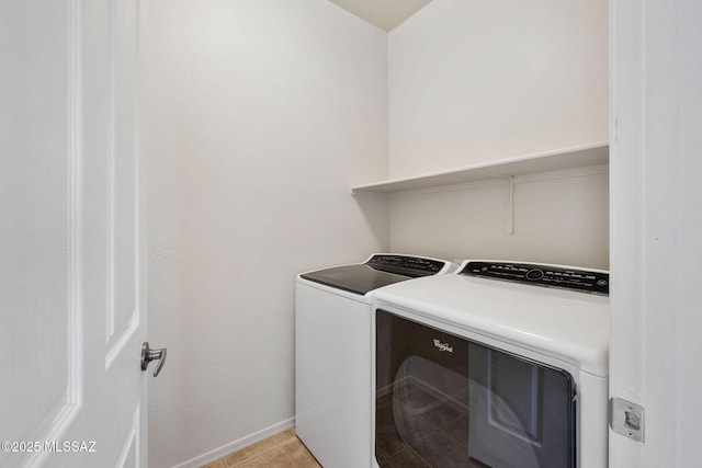 washroom featuring light tile patterned floors, baseboards, laundry area, and washing machine and clothes dryer