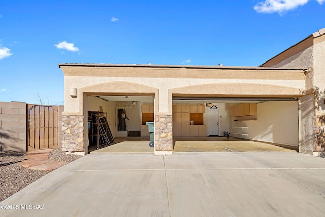 view of front of home featuring a garage, a gate, stucco siding, and concrete driveway
