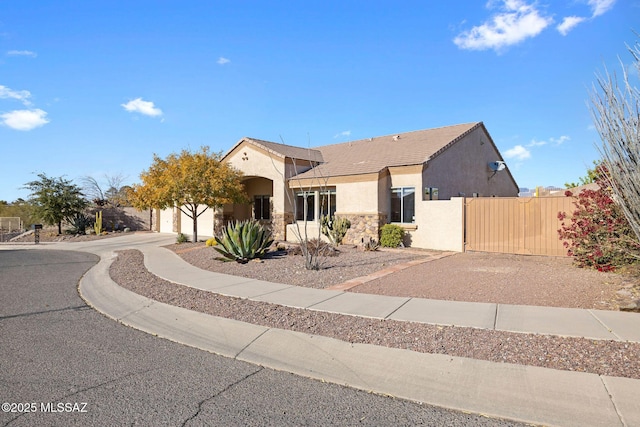 ranch-style house with a tiled roof, fence, stone siding, and stucco siding