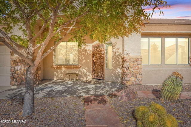 exterior space featuring stucco siding, a patio area, and stone siding