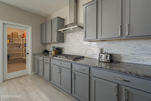5369 S Sierra Prieta Trl, Tucson, AZ 85747 - kitchen featuring dark stone countertops, gray cabinets, stainless steel gas cooktop, decorative backsplash, and wall chimney exhaust hood