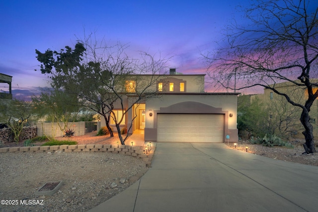 view of front of house with fence, stucco siding, an attached garage, and driveway