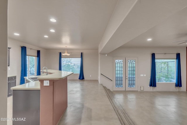 kitchen with open floor plan, a center island with sink, recessed lighting, light countertops, and a sink