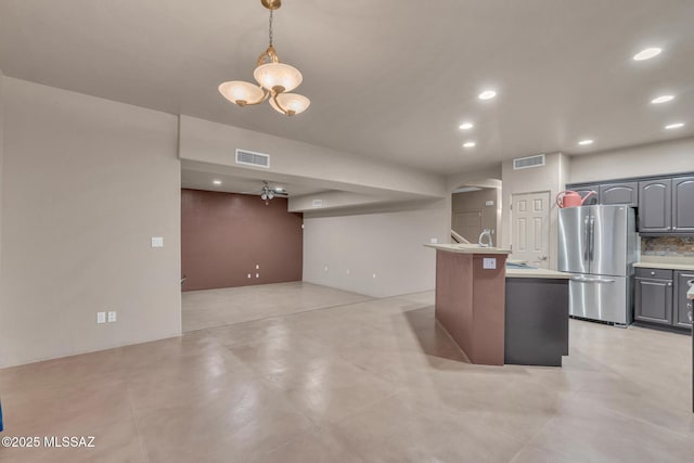 kitchen with freestanding refrigerator, arched walkways, visible vents, and light countertops