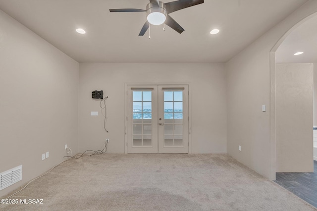 carpeted empty room featuring ceiling fan, arched walkways, french doors, recessed lighting, and visible vents