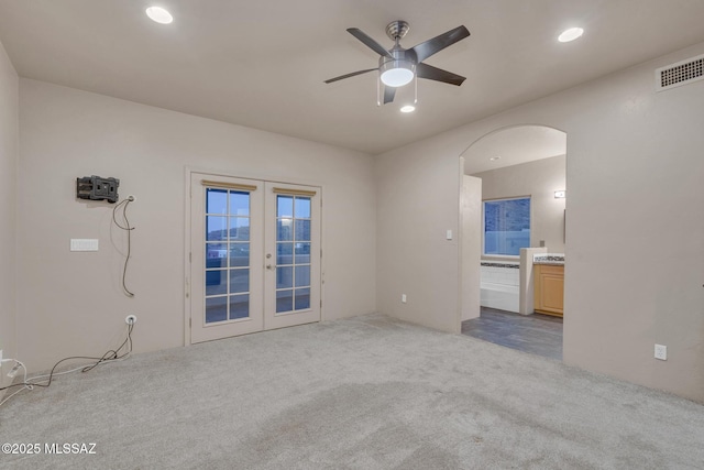 carpeted empty room with visible vents, recessed lighting, arched walkways, french doors, and a ceiling fan