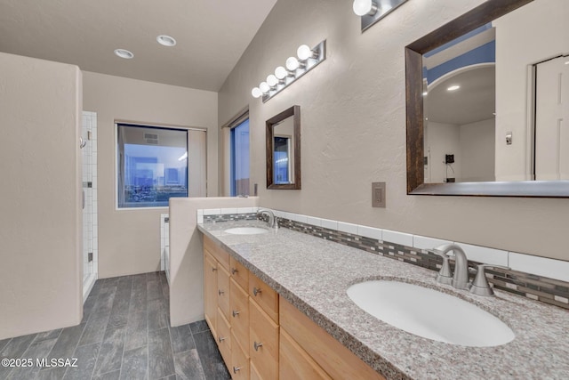 full bath featuring double vanity, a sink, wood finished floors, and tasteful backsplash