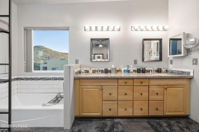 full bathroom with a sink, double vanity, a mountain view, and a bath