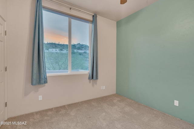 empty room featuring carpet floors, a ceiling fan, and a wealth of natural light