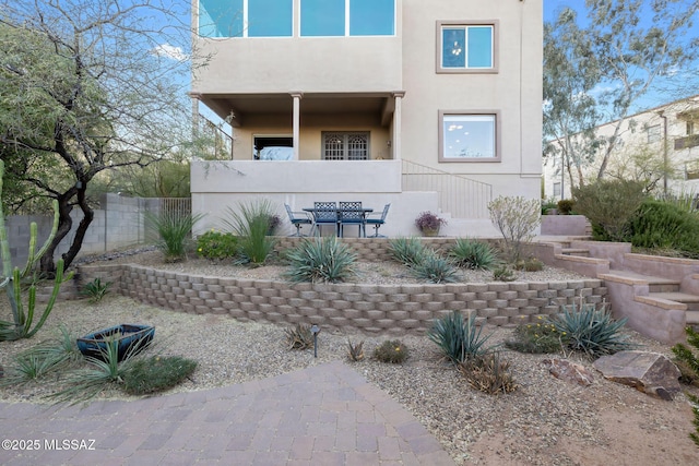 exterior space featuring fence, stairs, and stucco siding