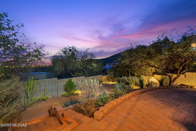 patio terrace at dusk with a mountain view and a fenced backyard