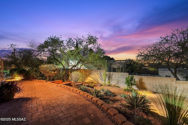 patio terrace at dusk featuring fence