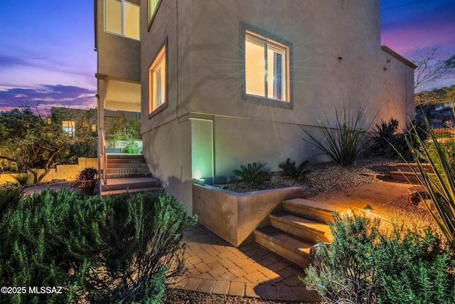 property exterior at dusk featuring stucco siding