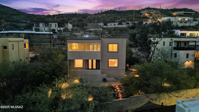 back of property at dusk featuring stucco siding and a mountain view