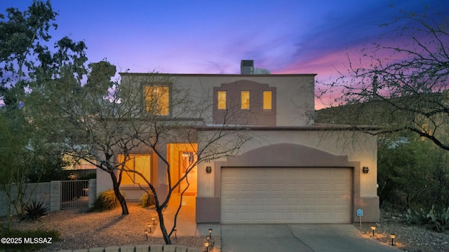 view of front facade featuring concrete driveway, fence, a chimney, and stucco siding
