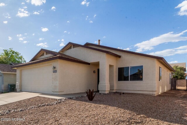 ranch-style home featuring concrete driveway, a garage, fence, and stucco siding