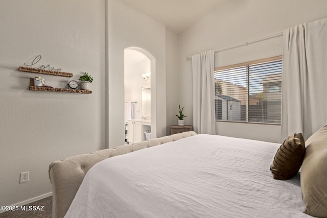 carpeted bedroom with arched walkways, baseboards, ensuite bath, and lofted ceiling