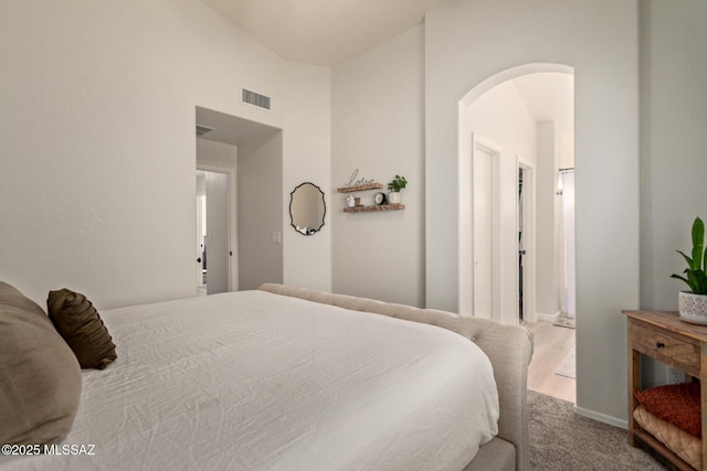 bedroom with carpet flooring, arched walkways, baseboards, and visible vents