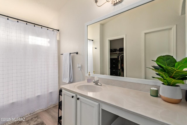 full bath featuring vanity, wood finished floors, and a walk in closet
