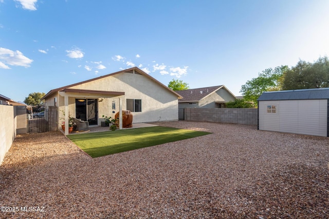 back of property with an outdoor structure, a fenced backyard, stucco siding, and a storage shed