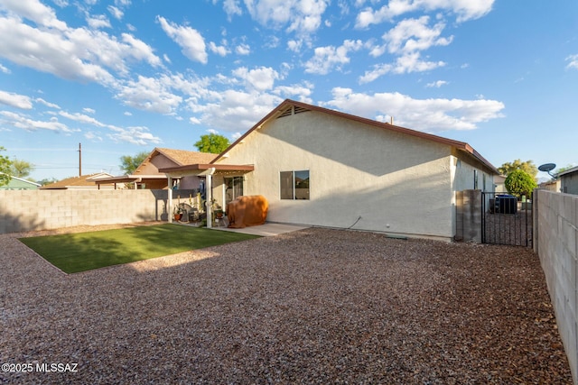 rear view of property with a fenced backyard, a patio, stucco siding, and central AC