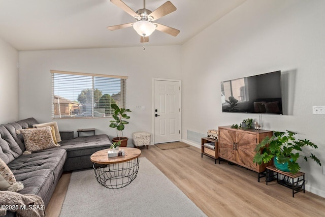 living area featuring baseboards, a ceiling fan, light wood-type flooring, and lofted ceiling