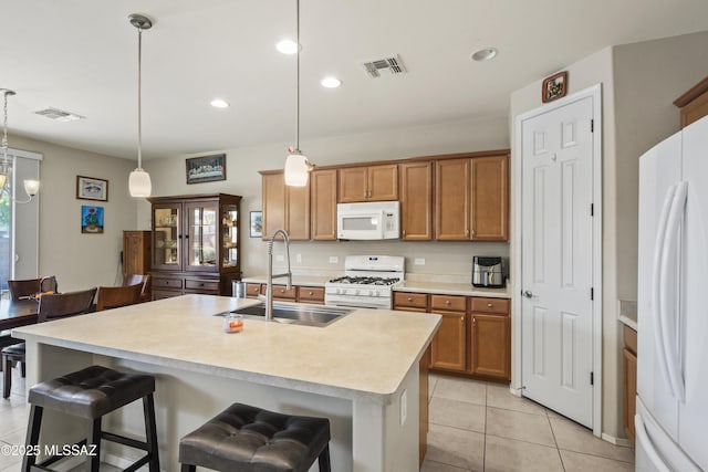 kitchen with visible vents, white appliances, brown cabinetry, and a sink