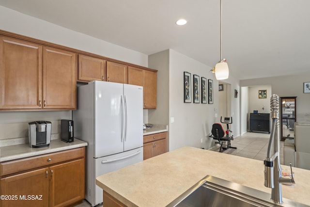 kitchen with freestanding refrigerator, brown cabinetry, and light countertops