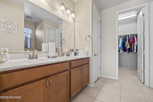 bathroom with a sink, tile patterned floors, a walk in closet, double vanity, and visible vents