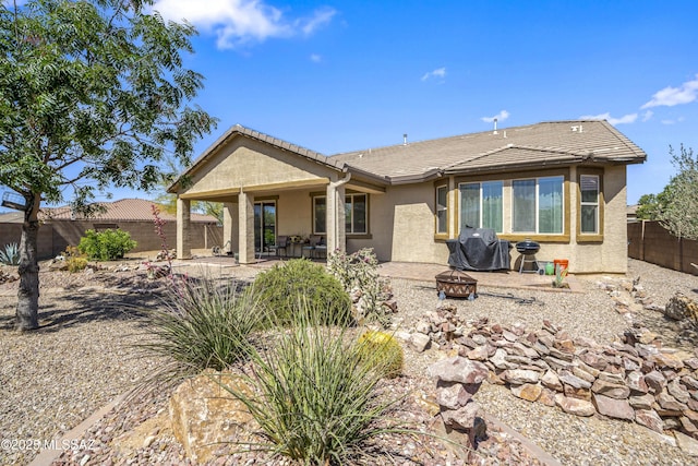 rear view of house featuring an outdoor fire pit, a fenced backyard, stucco siding, and a tiled roof