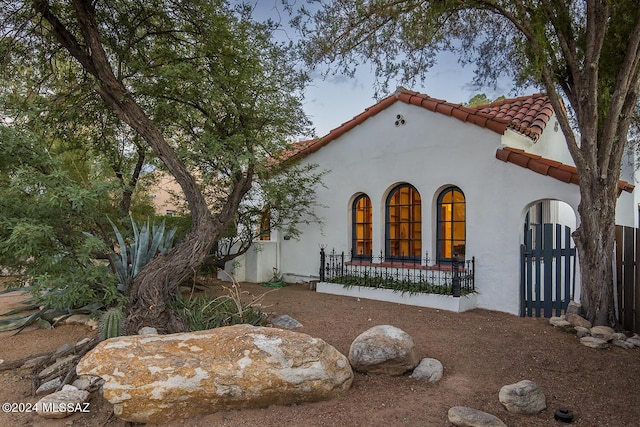 view of front of house with stucco siding, fence private yard, and a tiled roof