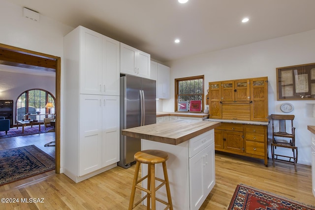 kitchen with freestanding refrigerator, white cabinetry, butcher block countertops, and light wood-style floors