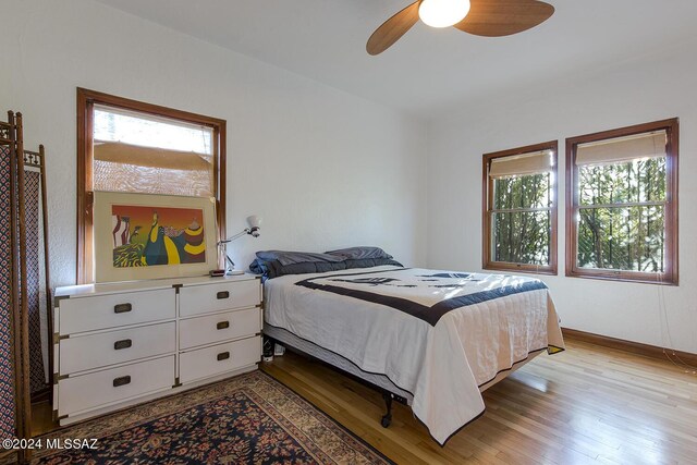 bedroom featuring baseboards, a ceiling fan, and light wood-style flooring