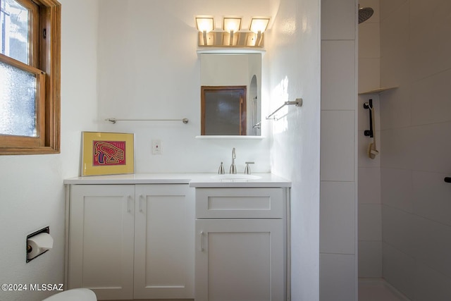 bathroom featuring tiled shower and vanity