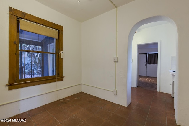unfurnished room featuring dark tile patterned flooring and arched walkways