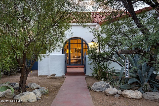 view of exterior entry featuring stucco siding and a tile roof
