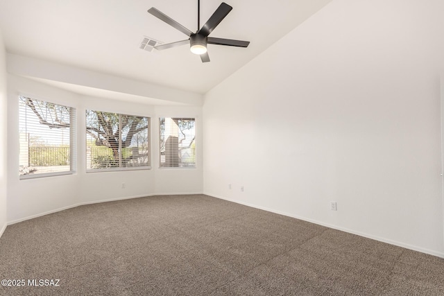 spare room with dark colored carpet, visible vents, a ceiling fan, and vaulted ceiling