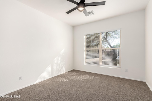 empty room with baseboards, visible vents, a ceiling fan, and carpet flooring