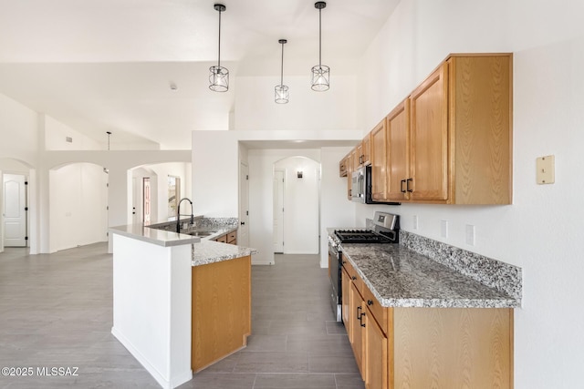 kitchen featuring stone counters, arched walkways, a sink, and stainless steel appliances