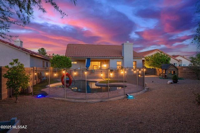 5305 N Via Ln, Doncella, Tucson, AZ 85750 - back of property at dusk featuring a chimney, a tile roof, a fenced backyard, and stucco siding