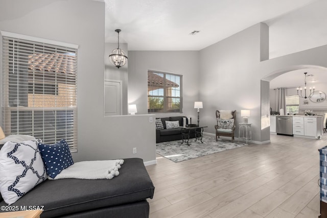 5305 N Via Ln, Doncella, Tucson, AZ 85750 - living room featuring a chandelier, plenty of natural light, arched walkways, light wood finished floors, and high vaulted ceiling