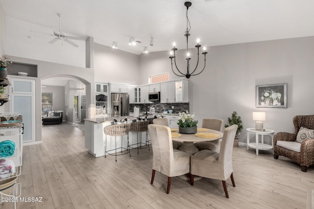 5305 N Via Ln, Doncella, Tucson, AZ 85750 - dining space featuring a towering ceiling, arched walkways, ceiling fan, light wood-style flooring, and baseboards