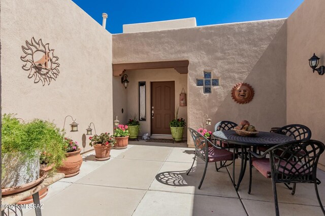 property entrance featuring a patio area, stucco siding, and outdoor dining space