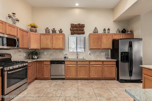 kitchen featuring tasteful backsplash, a sink, light stone counters, stainless steel appliances, and recessed lighting